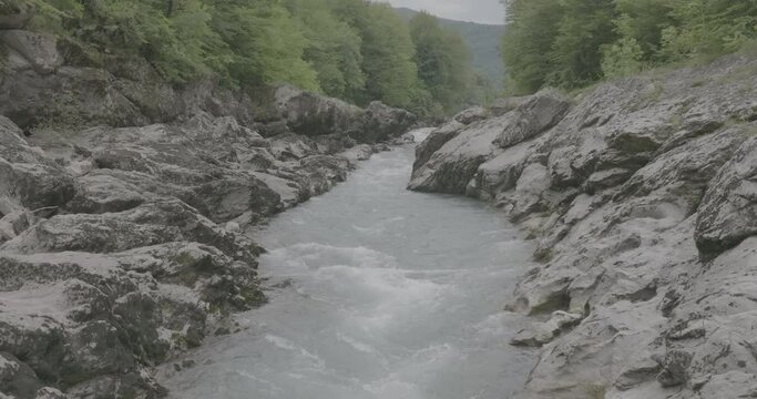 Aerial view of Mountain river and road. Flying over a mountain gorge. Slow motion 120 fps, ProRes 422, 10 bit ungraded DJI D-LOG video