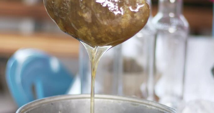 Close-up of a chef wrapping a beehive with white cloth to filter the honey.

