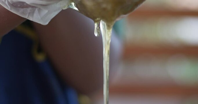 Close-up shot of honey filtered from a clean cheesecloth into a barrel.
