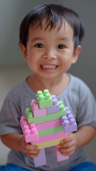 Happy child, cute asian toddler boy building house from plastic blocks sitting at floor.