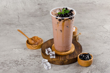 Boba or tapioca pearls is taiwan bubble milk tea in plastic cup with chocolate mint flavor on texture  background, summers refreshment. © ILHAM_PS
