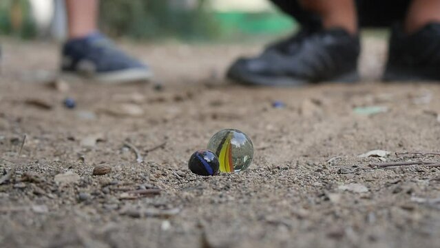 Close-up of kids playing marbles in the sand.