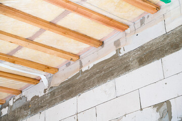 Insulated ceiling of a private house with a wooden crate. The roof is insulated with glass wool and sheathed with a vapor barrier, bottom view