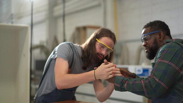 Accident during working with a machines in factory. Male carpenter having an accident while screwing on wood board.