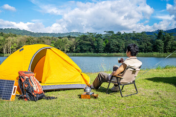 Young Asian traveling man relax and enjoy outdoor lifestyle camping in forest mountain on summer...