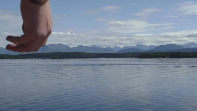 Slow motion shot of Caucasian, long haired, blonde young male doing a backflip gainer with scenic scandinavian mountains in the background in summer in Norway