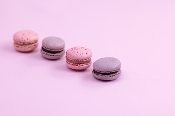 Purple and pink macaron cookies lie on a pink surface