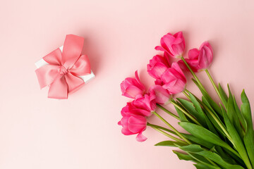 Gift or present box and tulips on pink table top view. Flat lay composition for birthday, mother day, saint Valentine day, wedding. Flyer, invitation, banner for your site, greeting card