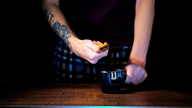 A man sharpens knives on a black background