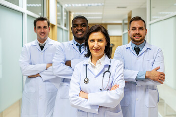 Portrait of successful team of medical doctors are looking at camera and smiling while standing in hospital