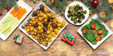 Different tasty dishes for Christmas dinner and gifts on wooden background