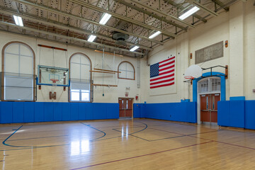 Nondescript US gymnasium with wood floors and blue wall padding found at a typical middle or high school.