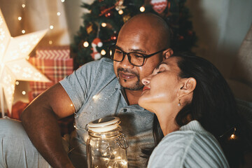 Happy interracial couple celebrating New Year at home together, sitting by Christmas tree