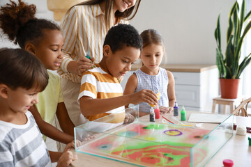 Little children with teacher during master class in Ebru painting at workshop