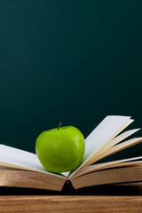 Green apple on book in front of the blackboard