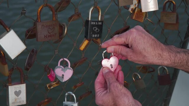Locking red heart padlock on fence of love lock bridge in Rotterdam.