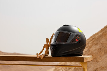 Motorcycle helmet and wooden mannequin on fence in desert