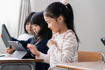 教室でタブレットPCを見る日本人小学生の女の子
