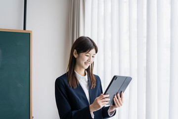 タブレットPCを見るスーツ姿の日本人女性