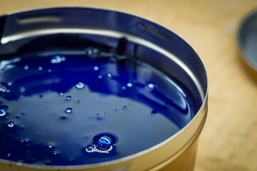 A can of cyan polygraph offset paint for the printing press. Special UV ink for printing. Open new can of blue paint. Selective focus