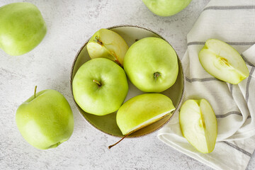 Bowl of fresh green apples on light table