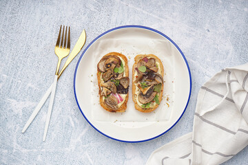 Plate of tasty toasts with cream cheese and mushrooms on light background