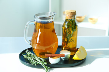 Board with spices, jug and bottle of fresh apple juice on table