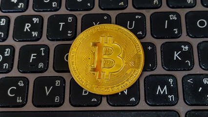 Bitcoin coins placed on the keyboard with Thai and English letters.