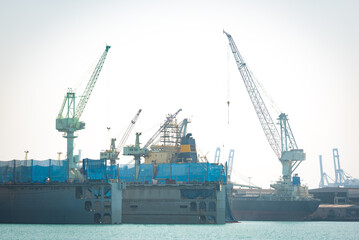 Obraz premium A crane is lifting loads in a shipyard.