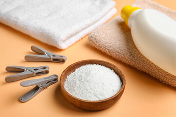 Laundry detergent, towels and clothespins on beige background, closeup