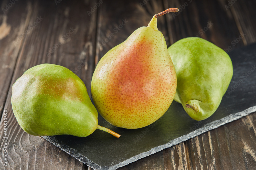 Poster Fresh pears on black stone on wooden background