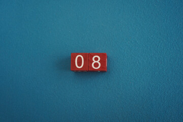 Wooden Viva Magenta cubes with number 8 blue background close-up top view. Concept of date or time. White numbers 8 on red cubes velvet background. Copy space for text or event. Blurred background