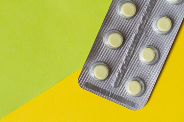 Blister with tablets on a yellow green background.