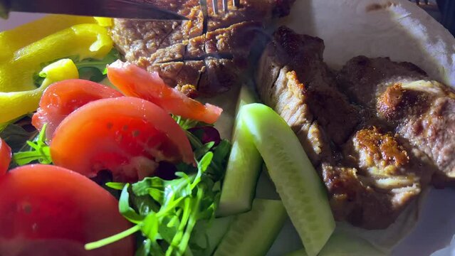 Knife and fork slicing into juicy grilled fillet steak cutting with knife and fork delicious grilled wagyu beef roast Fresh vegetables on plates with fried meat Cut off a piece of steak steam goes up