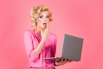 Beautiful sexy blonde pinup pop art woman on pink isolated background working with laptop.