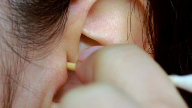 Woman hands cleaning the ear with the help of cotton swab stick close up