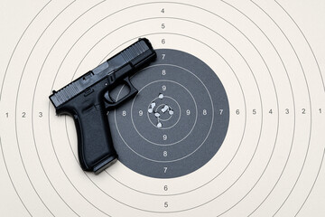 A compact 9mm pistol with a plastic frame and a target for shooting with bullet holes in the center.