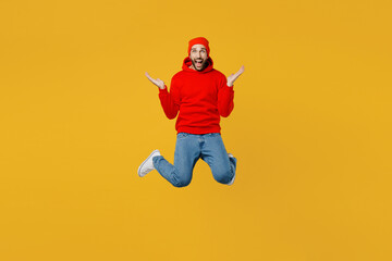 Fototapeta na wymiar Full body young exultant jubilant excited fun happy man in red hoody hat look camera jump high spread hands say wow isolated on plain yellow color background studio portrait People lifestyle concept