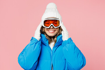 Snowboarder happy woman wear blue suit goggles hat ski padded jacket holding glasses mask look camera isolated on plain pastel pink background. Winter extreme sport hobby weekend trip relax concept.
