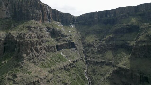 Aerial flight to huge dihedral cleft in stone escarpment cliff