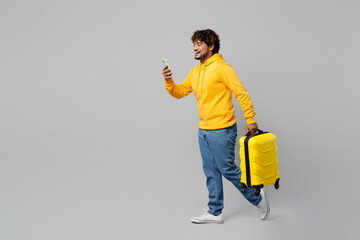 Full body traveler Indian man wear casual clothes hold suitcase valise passport ticket isolated on plain grey background Tourist travel abroad in free spare time rest getaway Air flight trip concept.