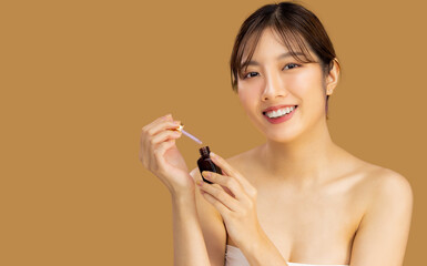 Beauty asian woman clean face applying by dropping serum, skin care healthy on beige color background.