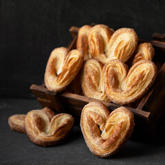 Puff pastries. Cookies ears in wooden box. Dark background.