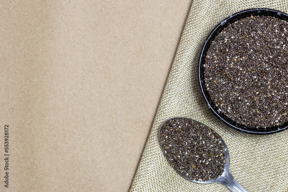 Wall mural healthy and diet food, chia seeds or superfood in black bowl with spoon on linen cloth