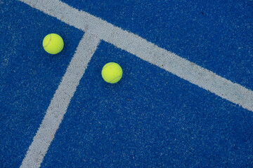 two tennis balls on a blue turf court paddle tennis court