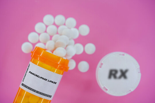 Pancrelipase Lipase Rx medicine pills in plactic vial with tablets. Pills spilling   from yellow container on pink background.