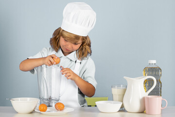 Child chef cook prepares food on isolated grey studio background. Kids cooking. Teen boy with apron...