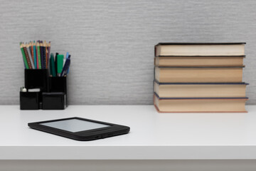 e-book lies on the table near paper books.