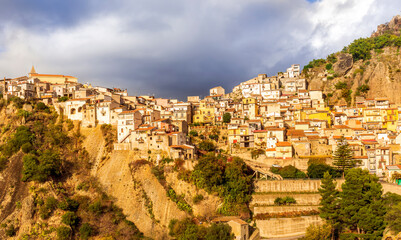 Obraz premium old mediterranean mountain dense town with levels of yellow houses and terraces on a mountain in evening light, vintage european village on a rock