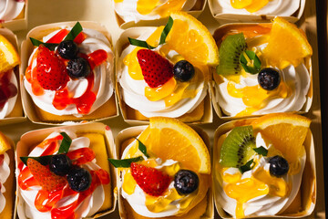 Close up on creamy cupcakes with jelly and fruits on top. Sweet dessert concept